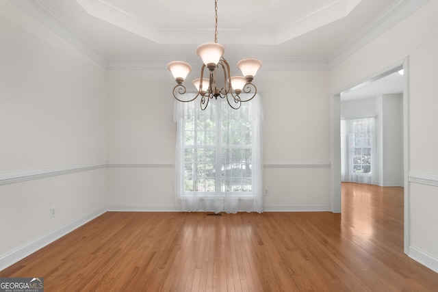unfurnished dining area with a chandelier, a tray ceiling, crown molding, baseboards, and hardwood / wood-style floors