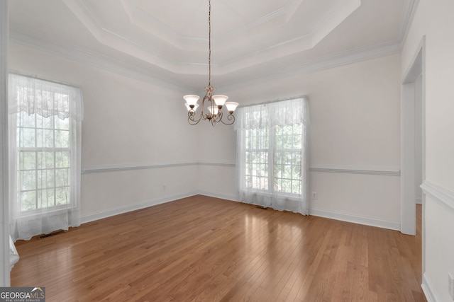 unfurnished dining area featuring wood finished floors, visible vents, a notable chandelier, crown molding, and a tray ceiling