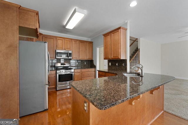 kitchen featuring a sink, stainless steel appliances, decorative backsplash, a kitchen bar, and a peninsula