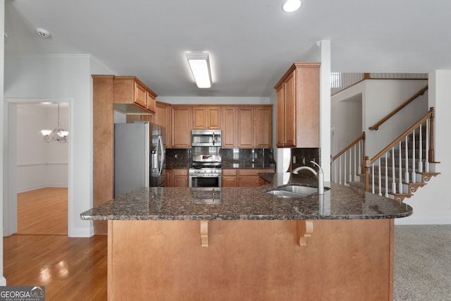 kitchen with tasteful backsplash, a breakfast bar, stainless steel appliances, a sink, and a peninsula