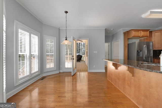 kitchen with a breakfast bar area, stainless steel refrigerator with ice dispenser, and a wealth of natural light
