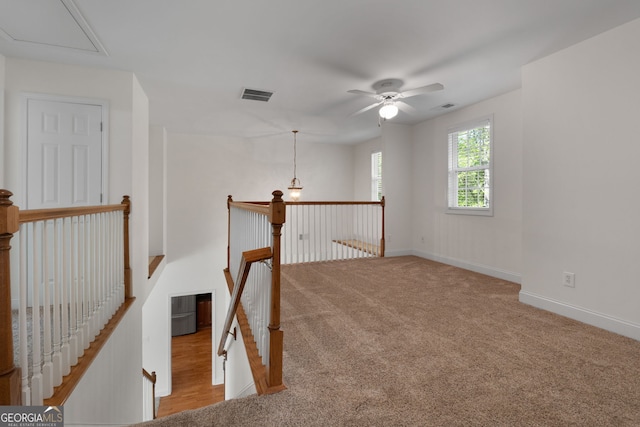 interior space featuring visible vents, attic access, an upstairs landing, and carpet