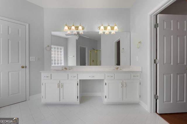 full bath with a sink, double vanity, a stall shower, baseboards, and tile patterned floors