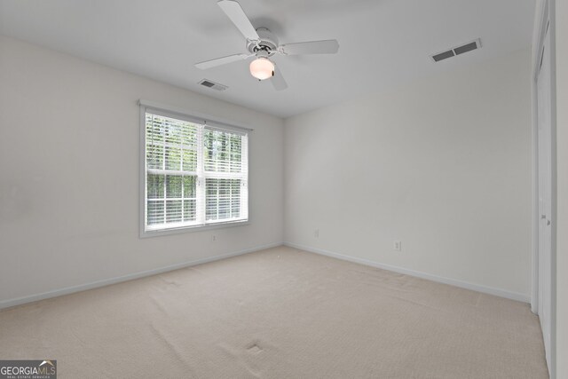 unfurnished room with visible vents, light colored carpet, and baseboards