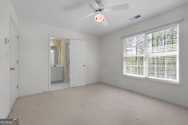 unfurnished bedroom with baseboards, visible vents, multiple windows, and light colored carpet