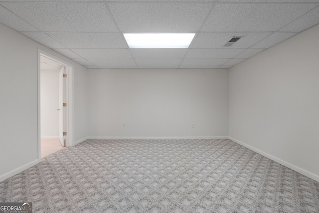 carpeted spare room with visible vents, a drop ceiling, and baseboards