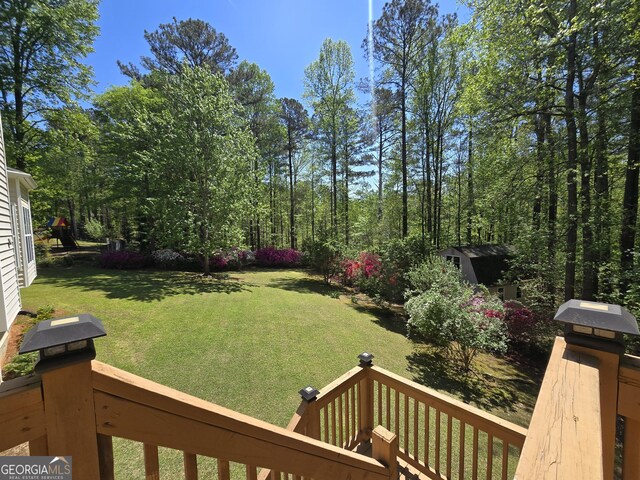 view of yard featuring a deck, a shed, and an outbuilding