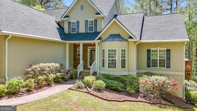 traditional-style home featuring a shingled roof and stucco siding