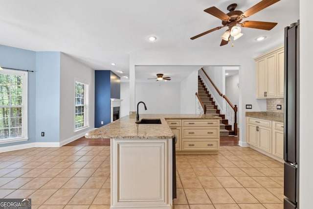 kitchen with stainless steel microwave, freestanding refrigerator, a sink, and cream cabinetry