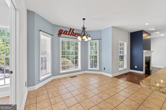 unfurnished sunroom featuring tile patterned floors, baseboards, visible vents, and a healthy amount of sunlight