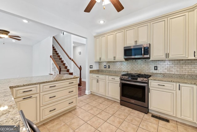 kitchen featuring a sink, backsplash, ceiling fan with notable chandelier, black appliances, and cream cabinets