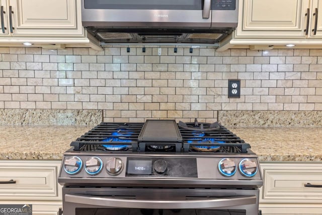 kitchen featuring dishwasher, a sink, a fireplace, cream cabinets, and ceiling fan