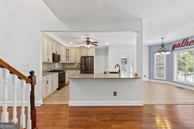 unfurnished living room featuring a fireplace with flush hearth, a sink, visible vents, ceiling fan with notable chandelier, and hardwood / wood-style floors