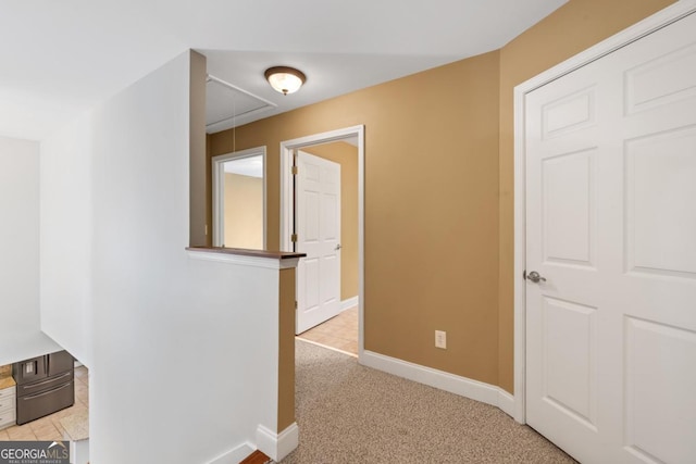 hall featuring baseboards, visible vents, and light colored carpet