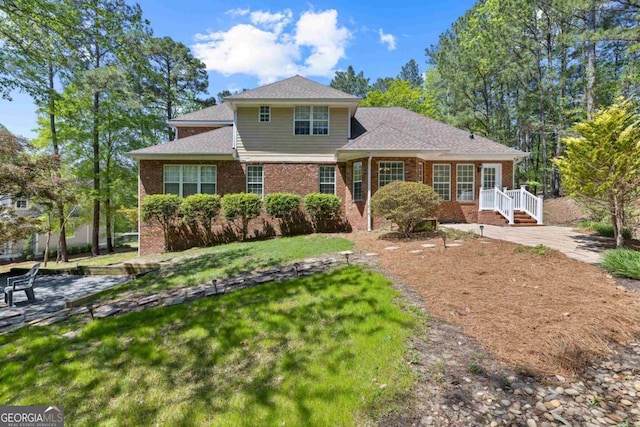 rear view of property with a patio area, a shingled roof, and brick siding