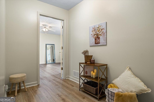 hallway with visible vents, baseboards, and wood finished floors