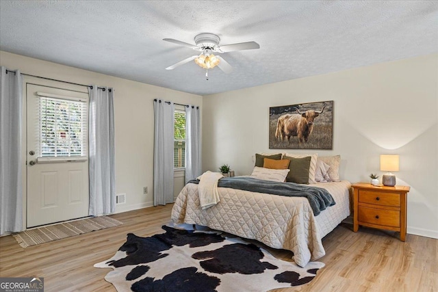 bedroom with light wood-style flooring, a textured ceiling, and baseboards