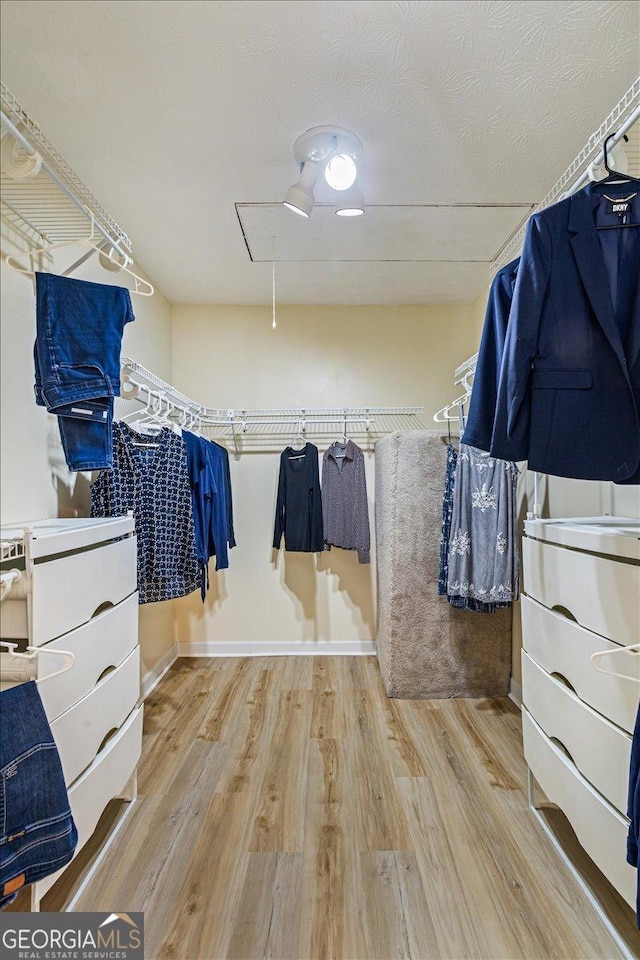 spacious closet with wood finished floors and attic access