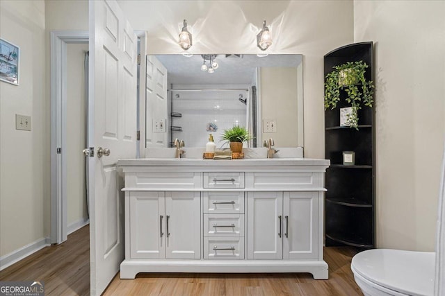 full bath featuring a shower, toilet, wood finished floors, a sink, and double vanity