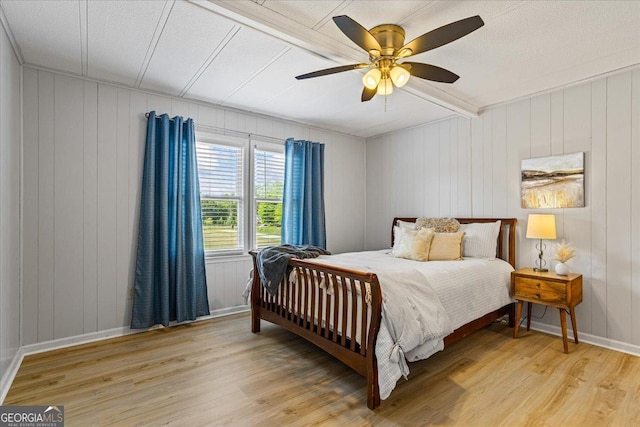 bedroom with light wood finished floors, baseboards, wooden walls, and ceiling fan