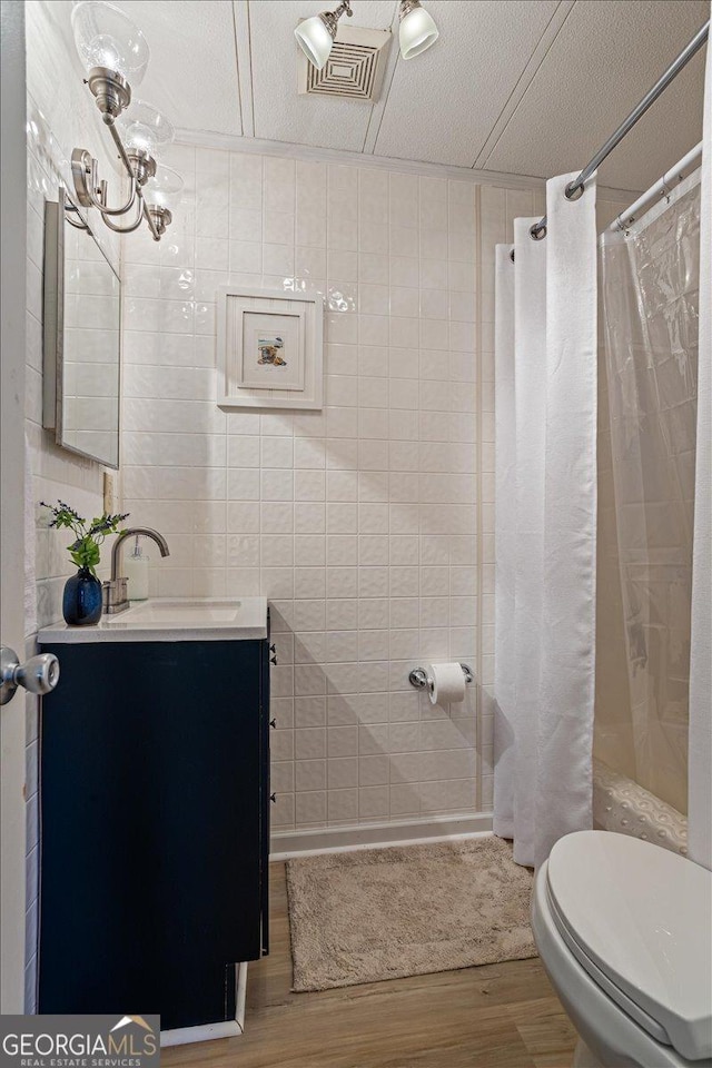 full bath with vanity, visible vents, toilet, wood finished floors, and tile walls