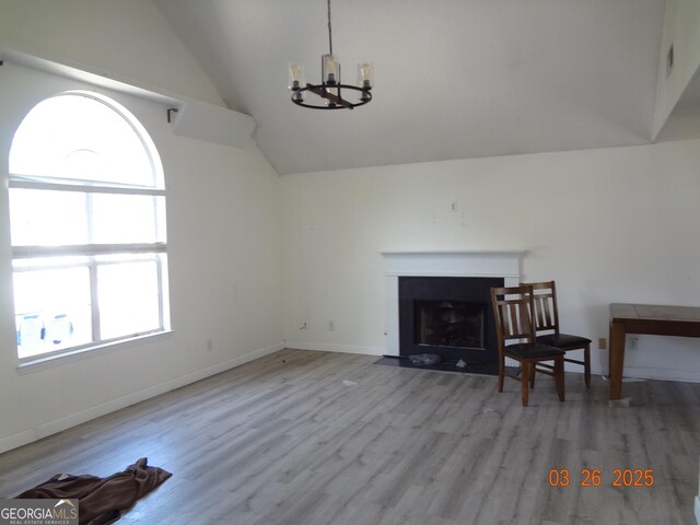 2338 Rambling Way, Lithonia, GA 30058 - living area featuring baseboards, an inviting chandelier, vaulted ceiling, wood finished floors, and a fireplace with flush hearth