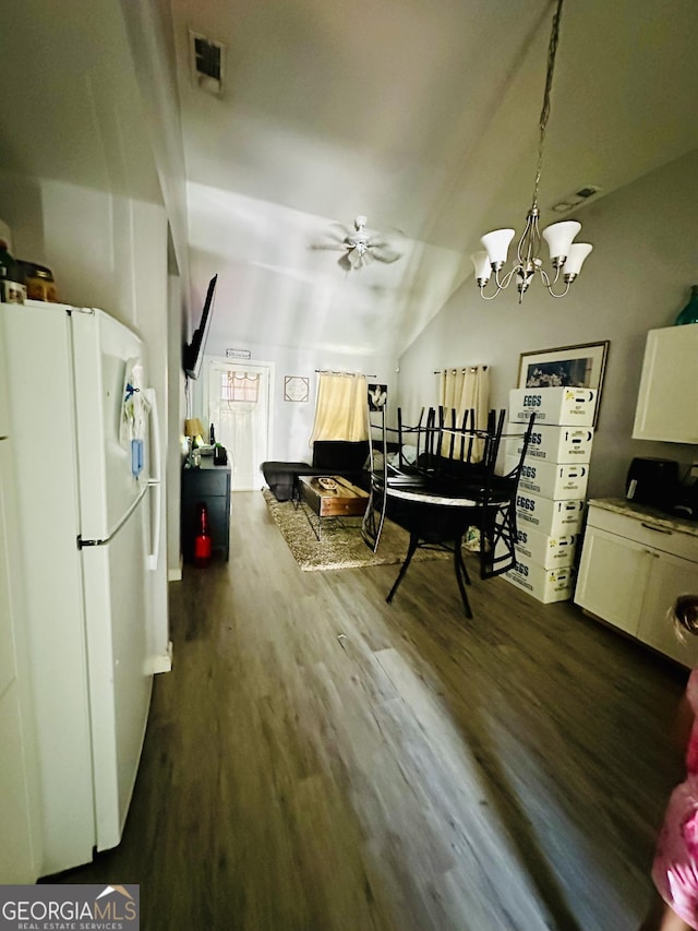 dining room featuring dark wood-style flooring, visible vents, vaulted ceiling, and ceiling fan with notable chandelier