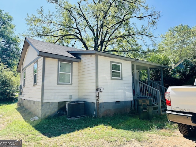 view of property exterior with a yard, central AC unit, crawl space, and a shingled roof