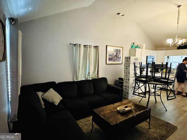 living area featuring a chandelier, visible vents, vaulted ceiling, and light wood-style flooring