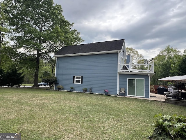 back of house featuring a balcony and a lawn