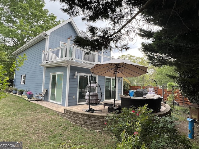 rear view of house with a patio, a balcony, and a lawn
