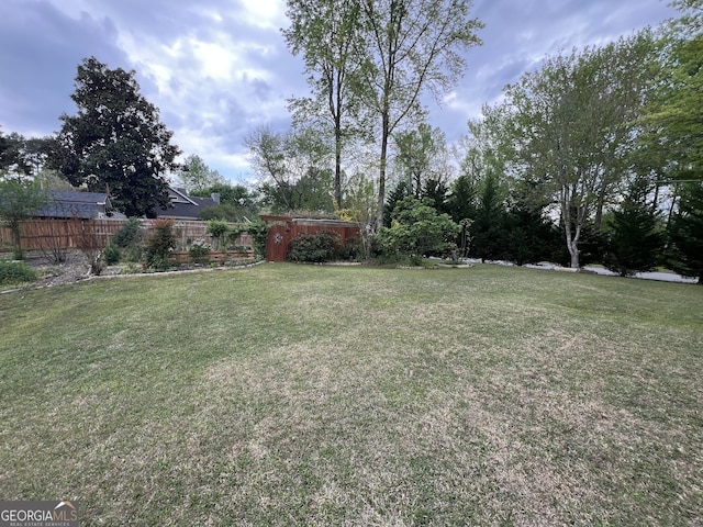 view of yard with fence, an outbuilding, and a storage unit