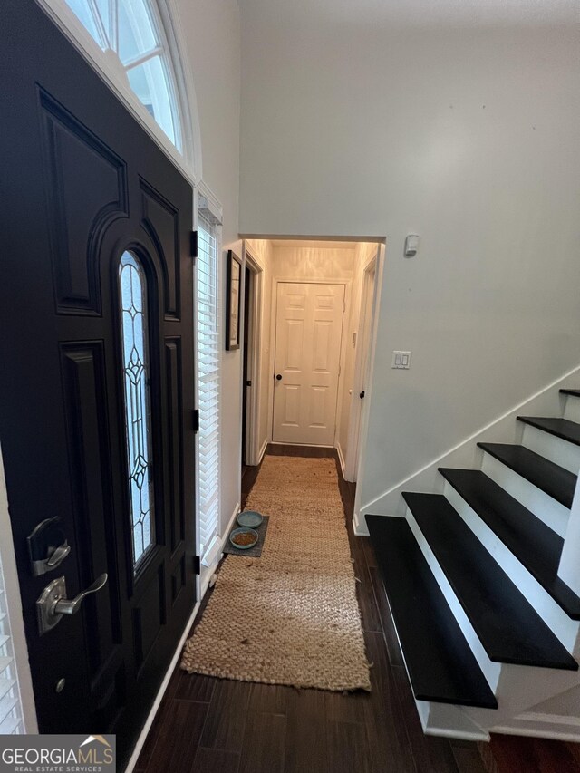 entrance foyer featuring a towering ceiling, wood finished floors, baseboards, and stairway