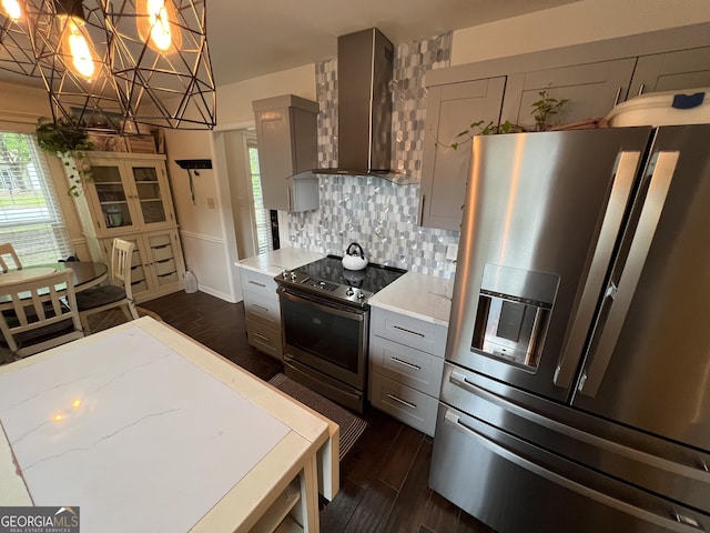 kitchen with dark wood-type flooring, wall chimney range hood, appliances with stainless steel finishes, and gray cabinetry
