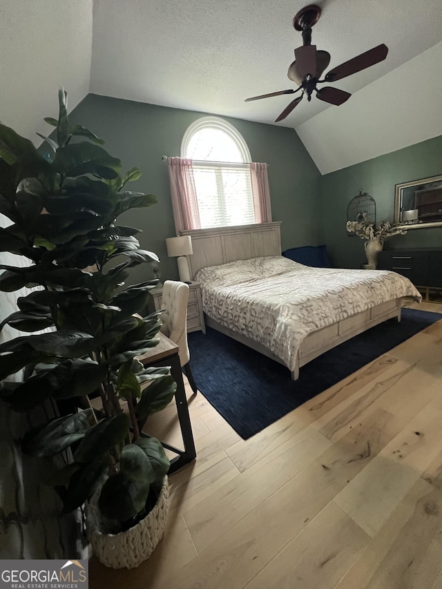 bedroom featuring a textured ceiling, wood finished floors, and lofted ceiling