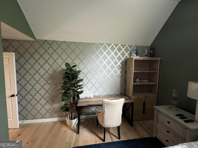 interior space featuring baseboards, vaulted ceiling, wood finished floors, and wallpapered walls