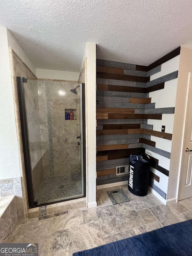 full bath featuring wood walls, a stall shower, and a textured ceiling