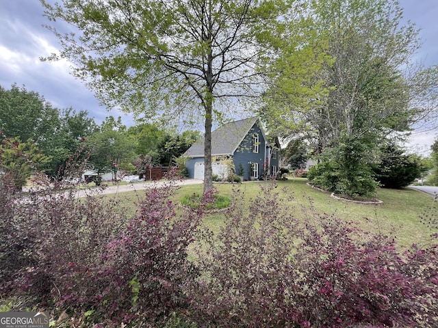 view of yard with a garage and driveway