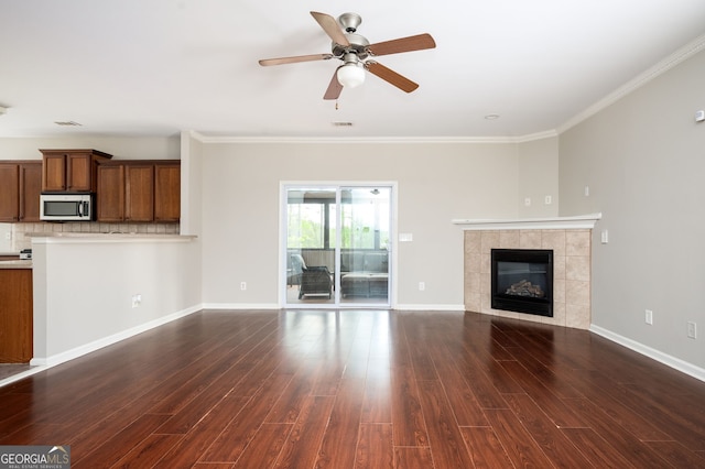 67 Ryans Pt, Dallas, GA 30132 - unfurnished living room with crown molding, a tile fireplace, a ceiling fan, and dark wood-style floors