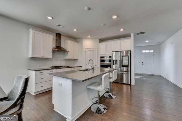 5530 Bower Pl, Cumming, GA 30028 - kitchen with visible vents, wall chimney exhaust hood, decorative backsplash, stainless steel appliances, and a sink