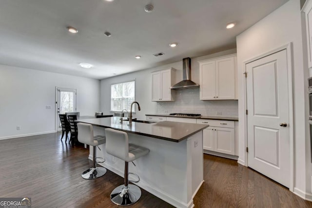 5530 Bower Pl, Cumming, GA 30028 - kitchen with wall chimney exhaust hood, dark wood finished floors, a kitchen breakfast bar, stainless steel gas cooktop, and a sink