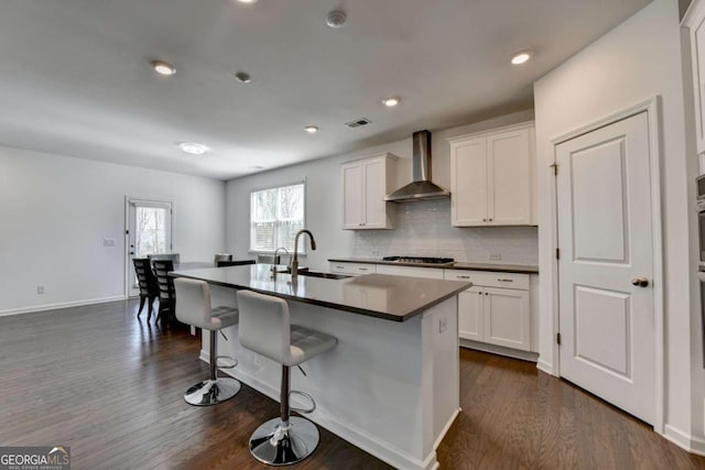 5530 Bower Pl, Cumming, GA 30028 - kitchen featuring a kitchen breakfast bar, wall chimney range hood, dark wood-style floors, stainless steel gas cooktop, and a sink