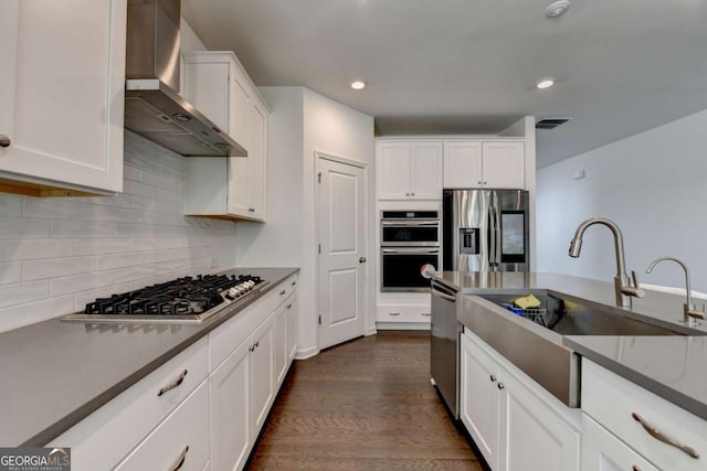 5530 Bower Pl, Cumming, GA 30028 - kitchen with wall chimney exhaust hood, white cabinets, appliances with stainless steel finishes, a sink, and dark wood-style floors