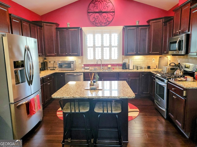 kitchen featuring a center island, a sink, appliances with stainless steel finishes, dark wood-style floors, and vaulted ceiling
