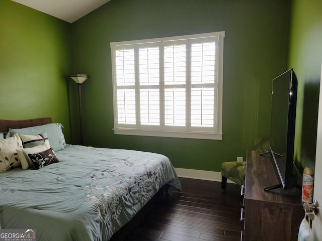 bedroom featuring lofted ceiling, baseboards, and dark wood-style floors