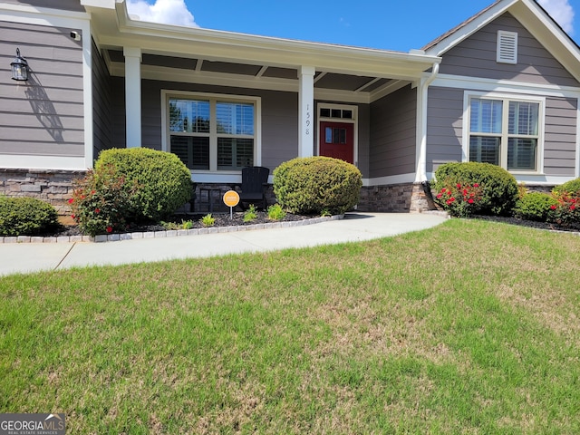 view of front of house featuring stone siding, covered porch, and a front yard
