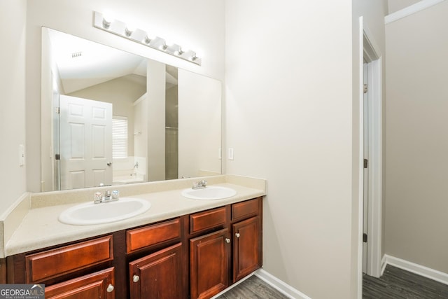bathroom featuring a sink, baseboards, double vanity, and a garden tub