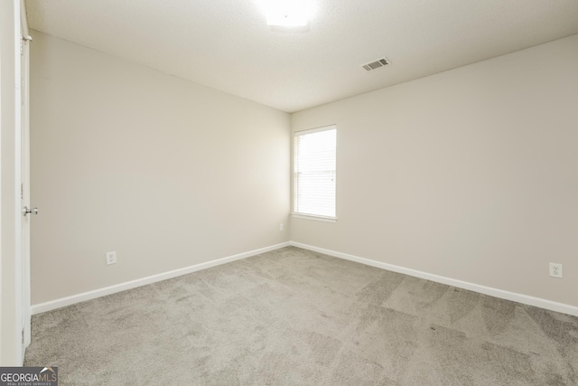 carpeted spare room with visible vents and baseboards
