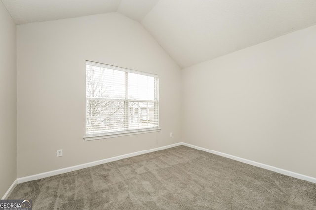 carpeted empty room with baseboards and vaulted ceiling
