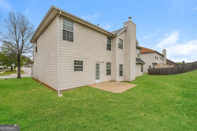 back of property with a yard, a patio area, fence, and a chimney